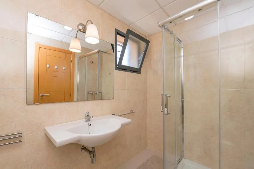 A bathroom with a wall-mounted sink and glass shower.