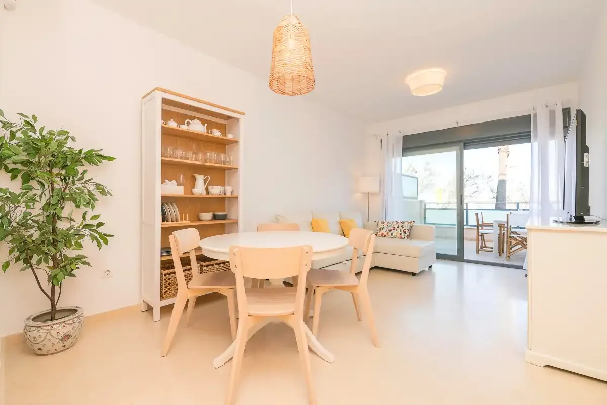 A bright dining and living area with a round table and seating beside sliding glass doors.