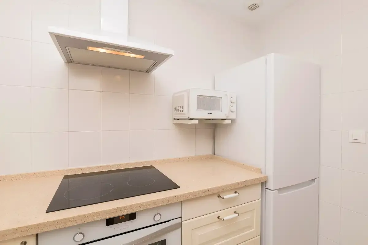 A bright kitchen with a cooktop, microwave, and refrigerator.