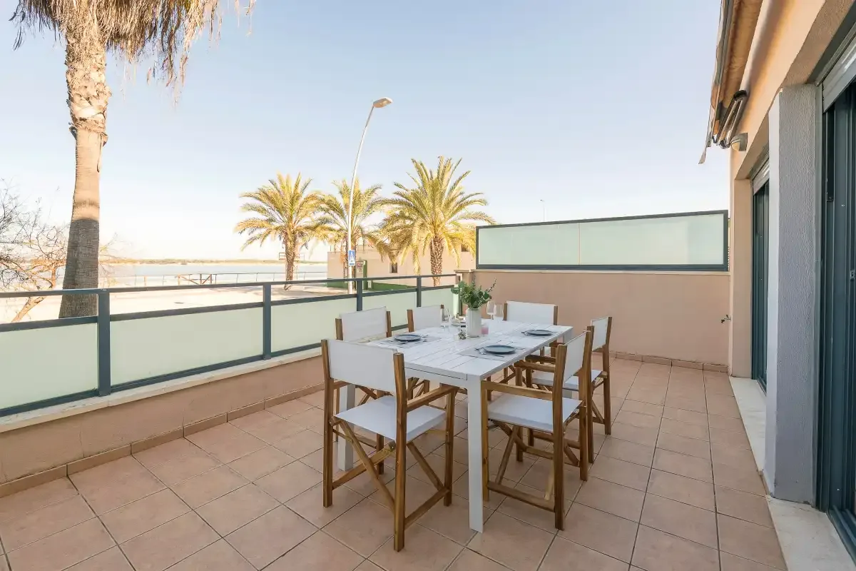 A tiled outdoor terrace with a dining table and chairs beside a railing.