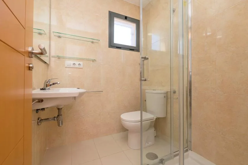 A tiled bathroom with a sink, toilet, and glass shower.