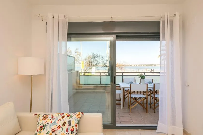 A bright living area opens onto a balcony with a dining table and chairs.