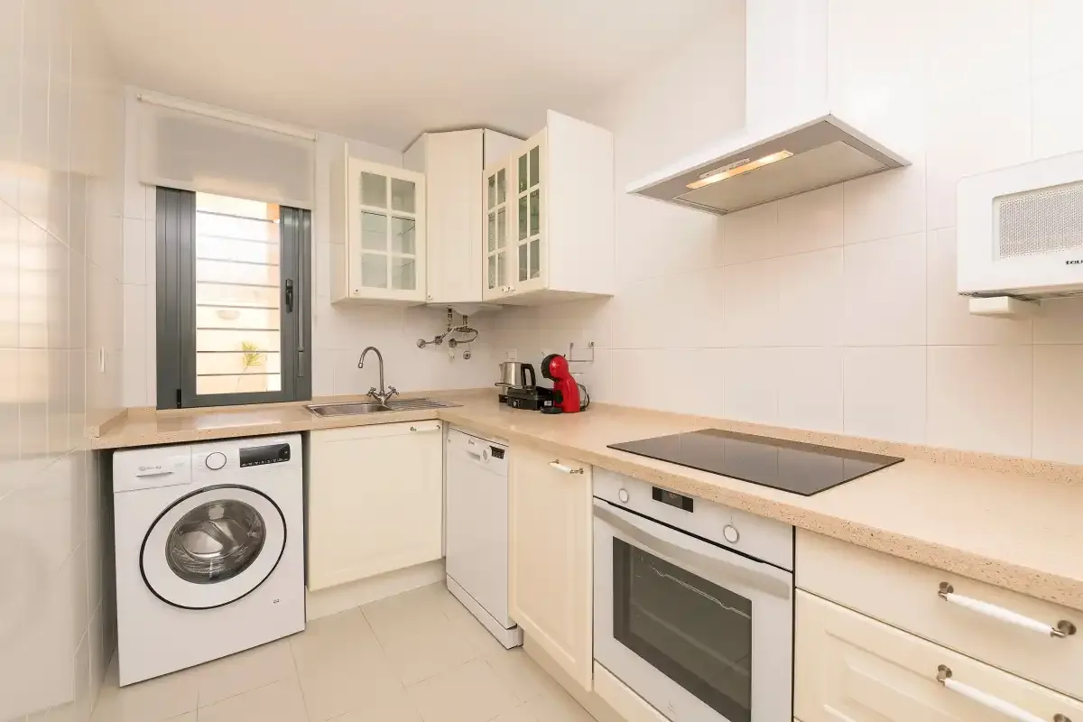 A bright kitchen with a washing machine and built-in oven.