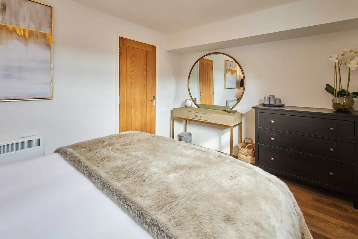 A bedroom with a bed, a wooden door, and a dresser.