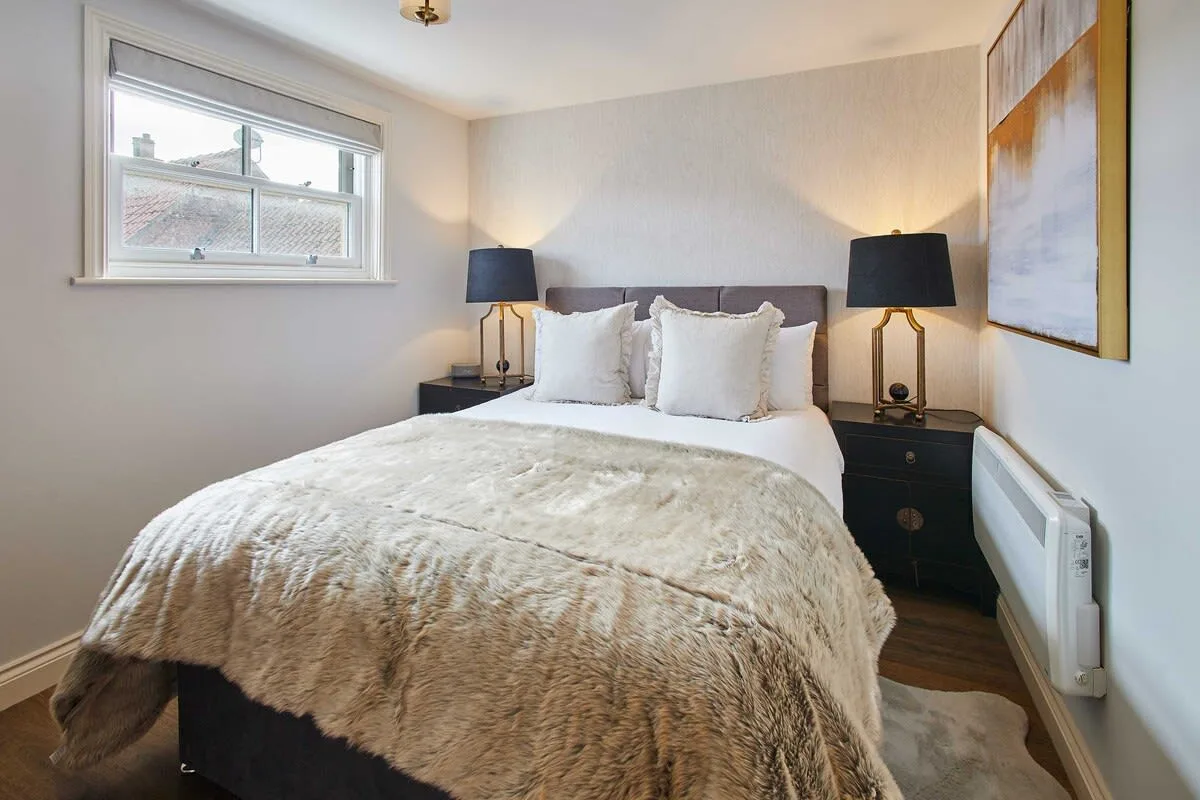 A bedroom with a neatly made bed and matching bedside tables.