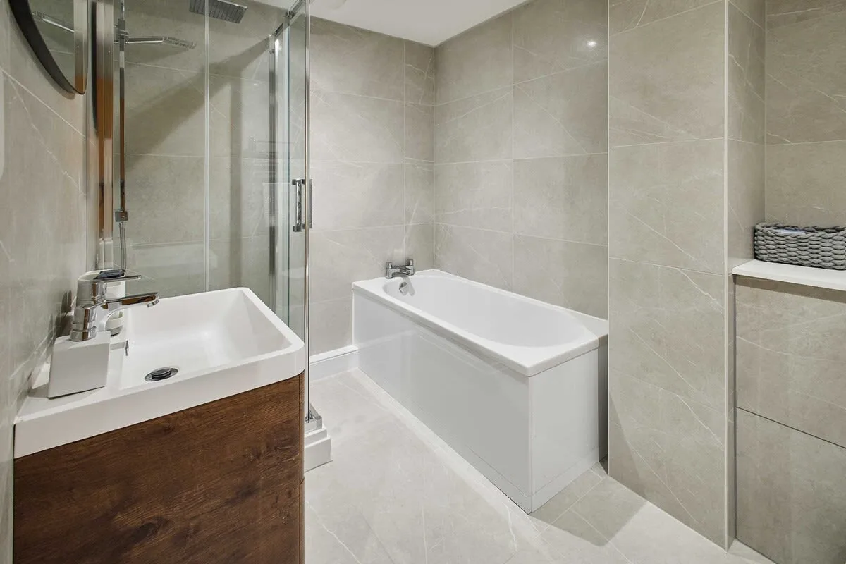 A tiled bathroom with a bathtub, glass shower, and sink.