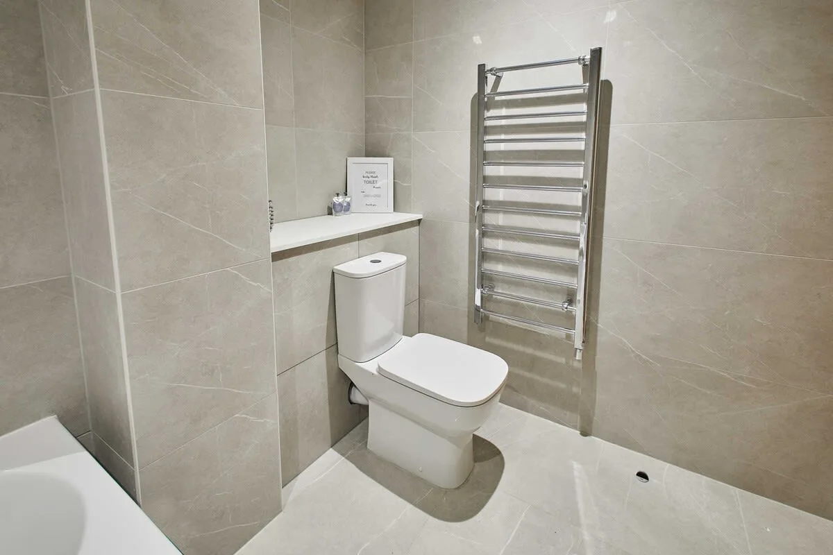 A tiled bathroom with a toilet and wall-mounted heated towel rail.