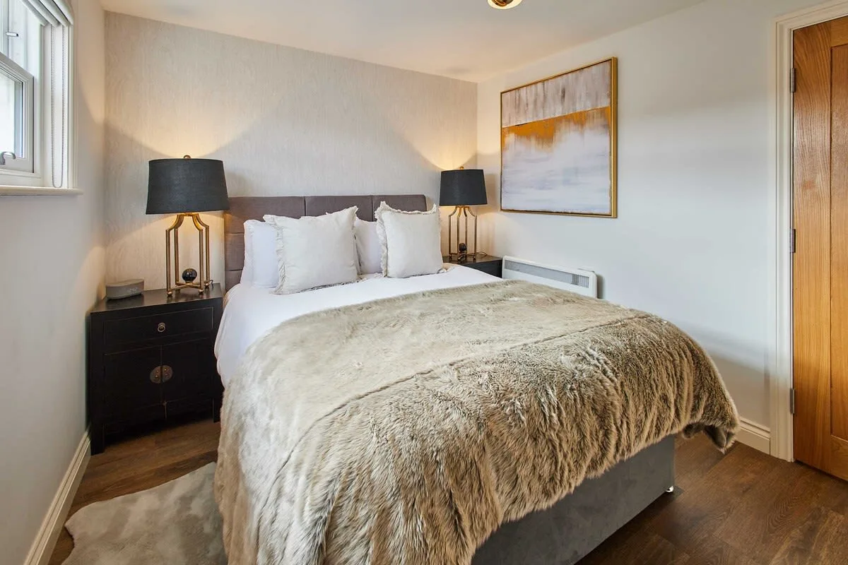 A bedroom with a neatly made bed and matching bedside lamps.