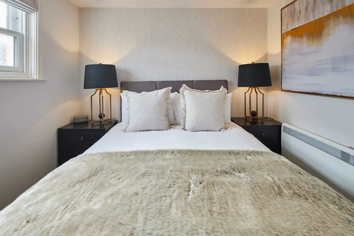 A bedroom with a neatly made bed and matching bedside lamps.