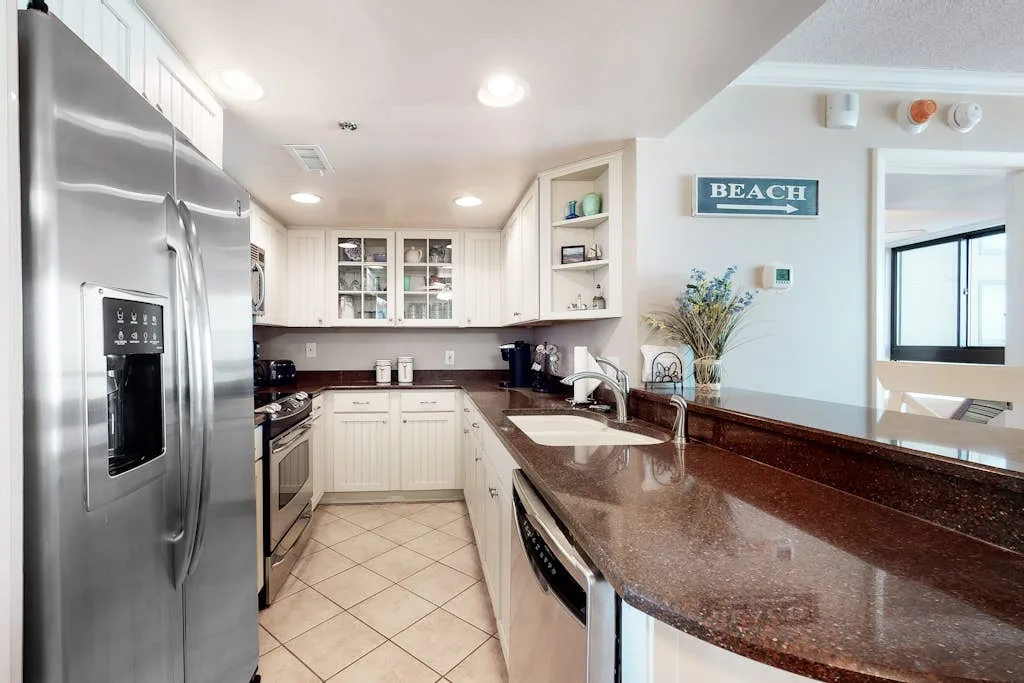 Kitchen with white cabinetry, stainless steel appliances, and a long brown countertop.
