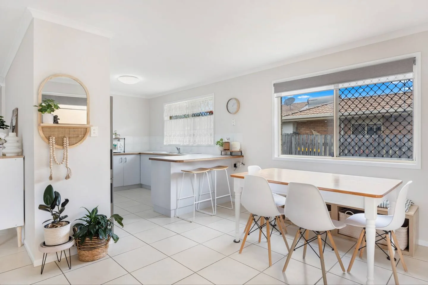 A bright dining area with a table and chairs sits beside an open kitchen.