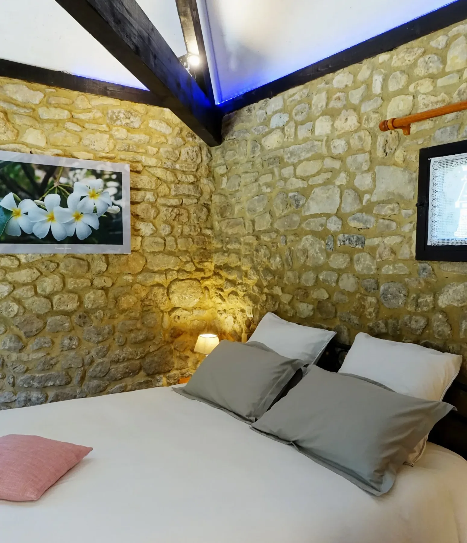 Habitación La Borie con una cama de 160 × 200 cm, flores blancas, pared de piedra e iluminación