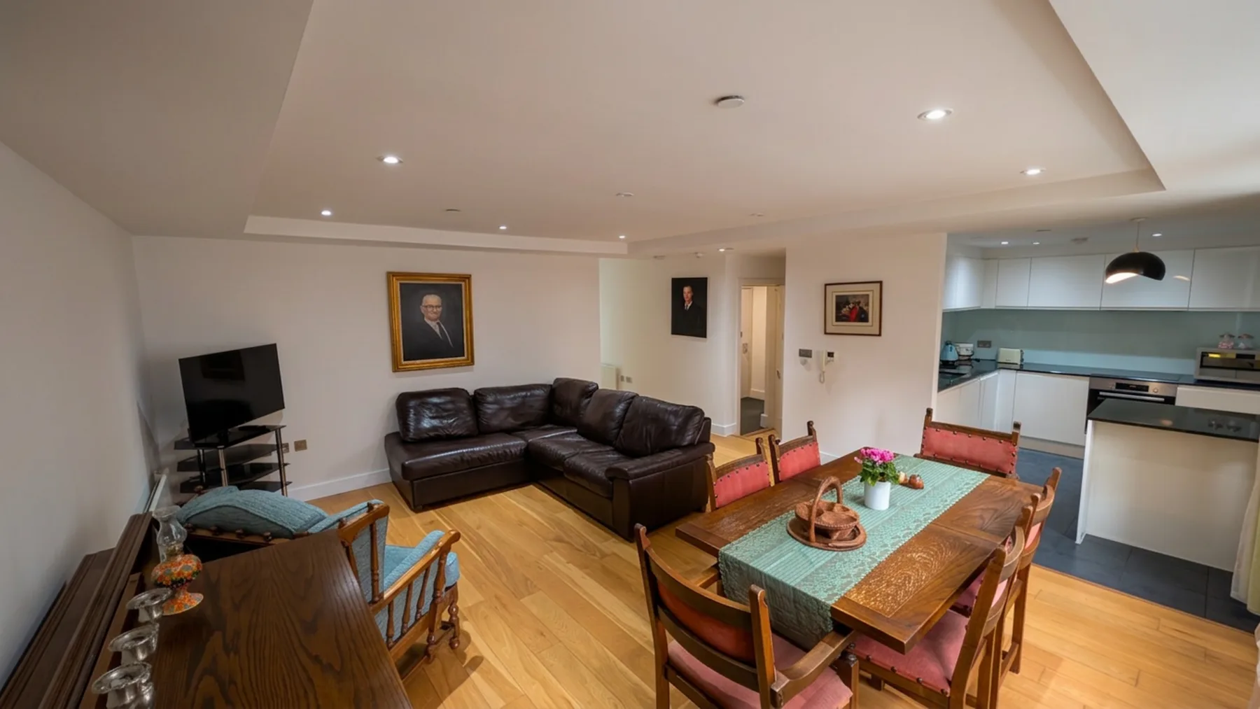 Una sala de estar y comedor con asientos, una mesa de madera y una cocina abierta.