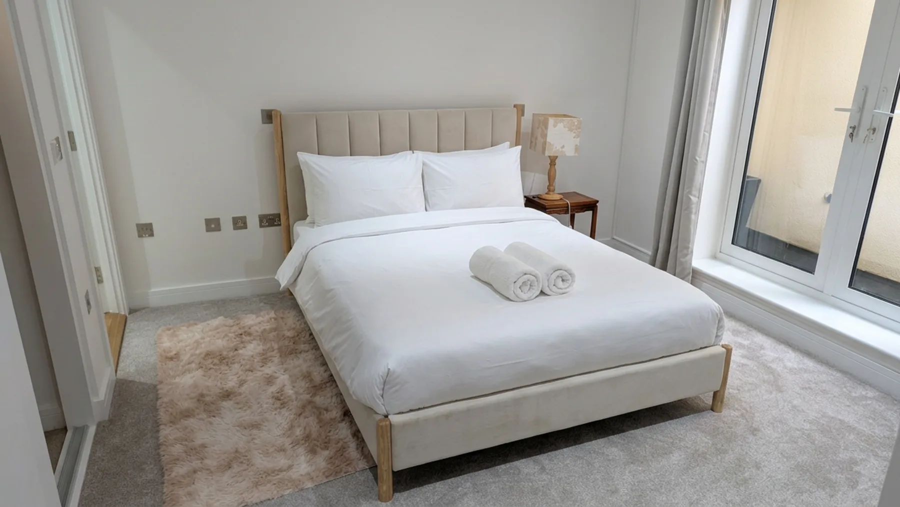 Un dormitorio con una cama bien tendida y toallas dobladas.