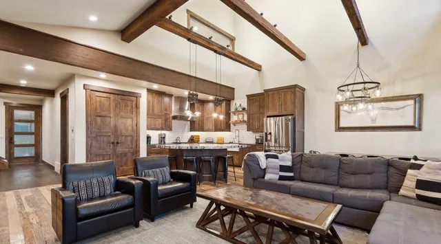 A spacious living room with dark seating, a wood coffee table, and an open kitchen.