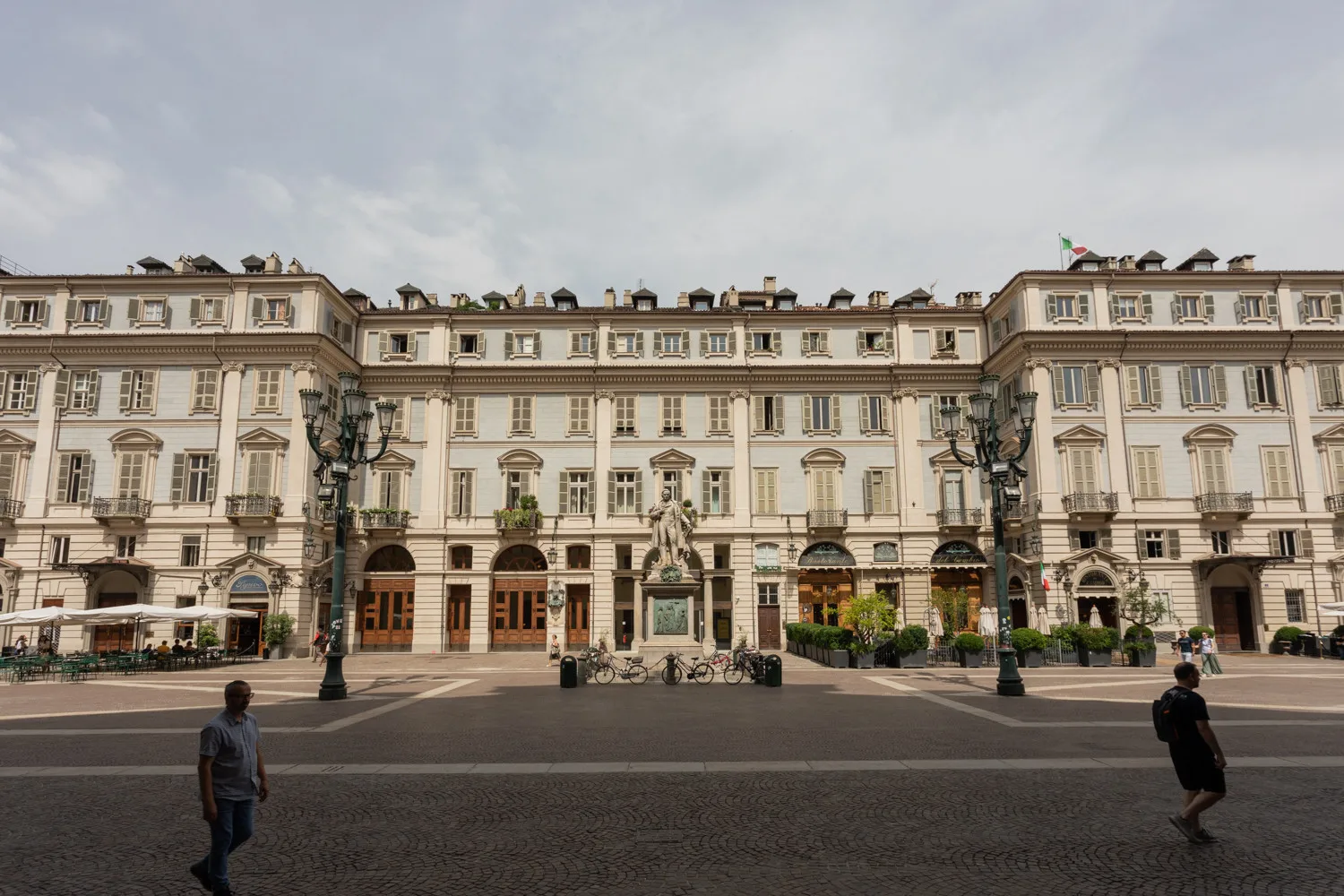 A grand historic building with ornate windows faces a broad paved plaza.