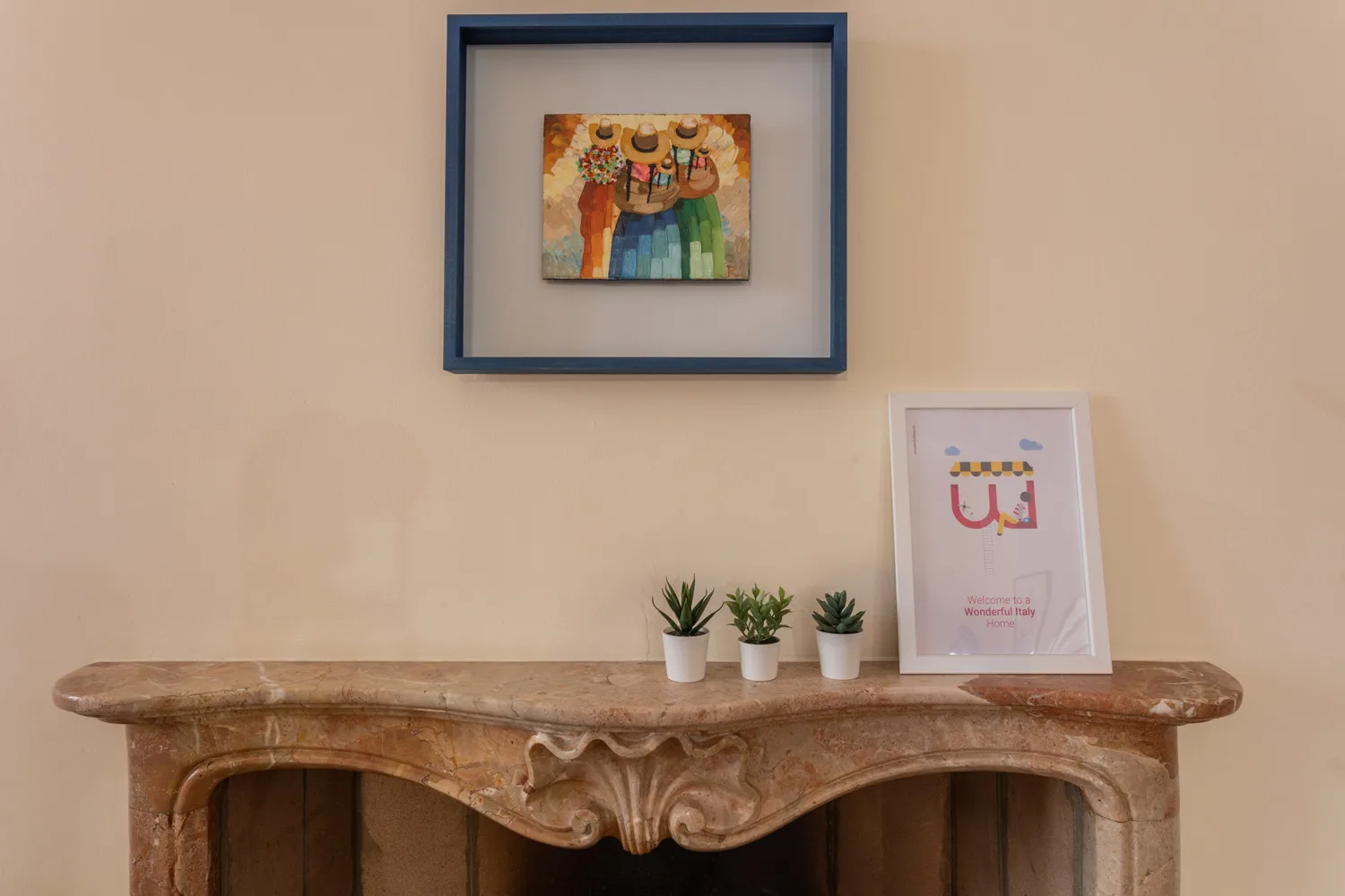 Una repisa decorativa exhibe cuadros y pequeñas plantas en macetas.