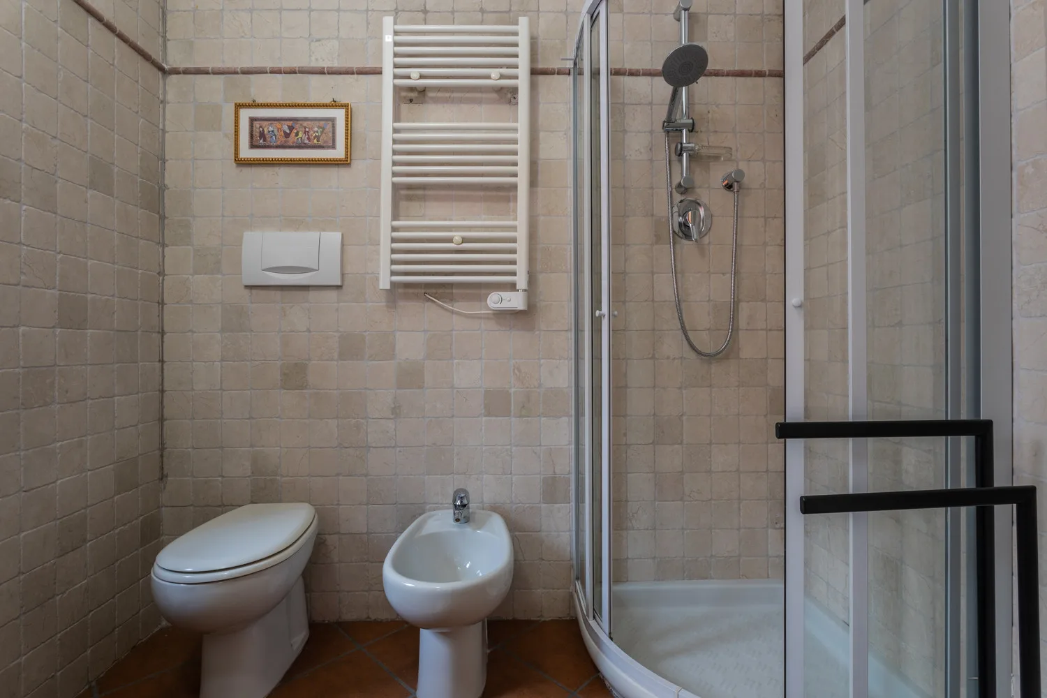 Un baño con azulejos, inodoro, lavabo y ducha de vidrio.
