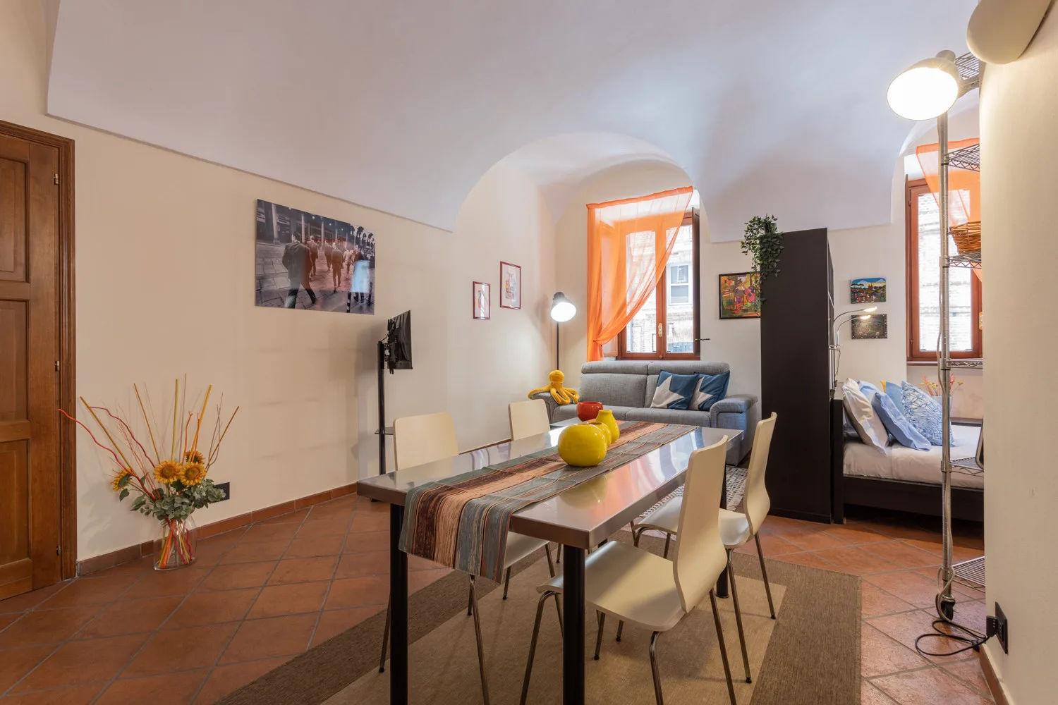 Una zona de comedor y estar con una mesa, asientos y ventanas luminosas.