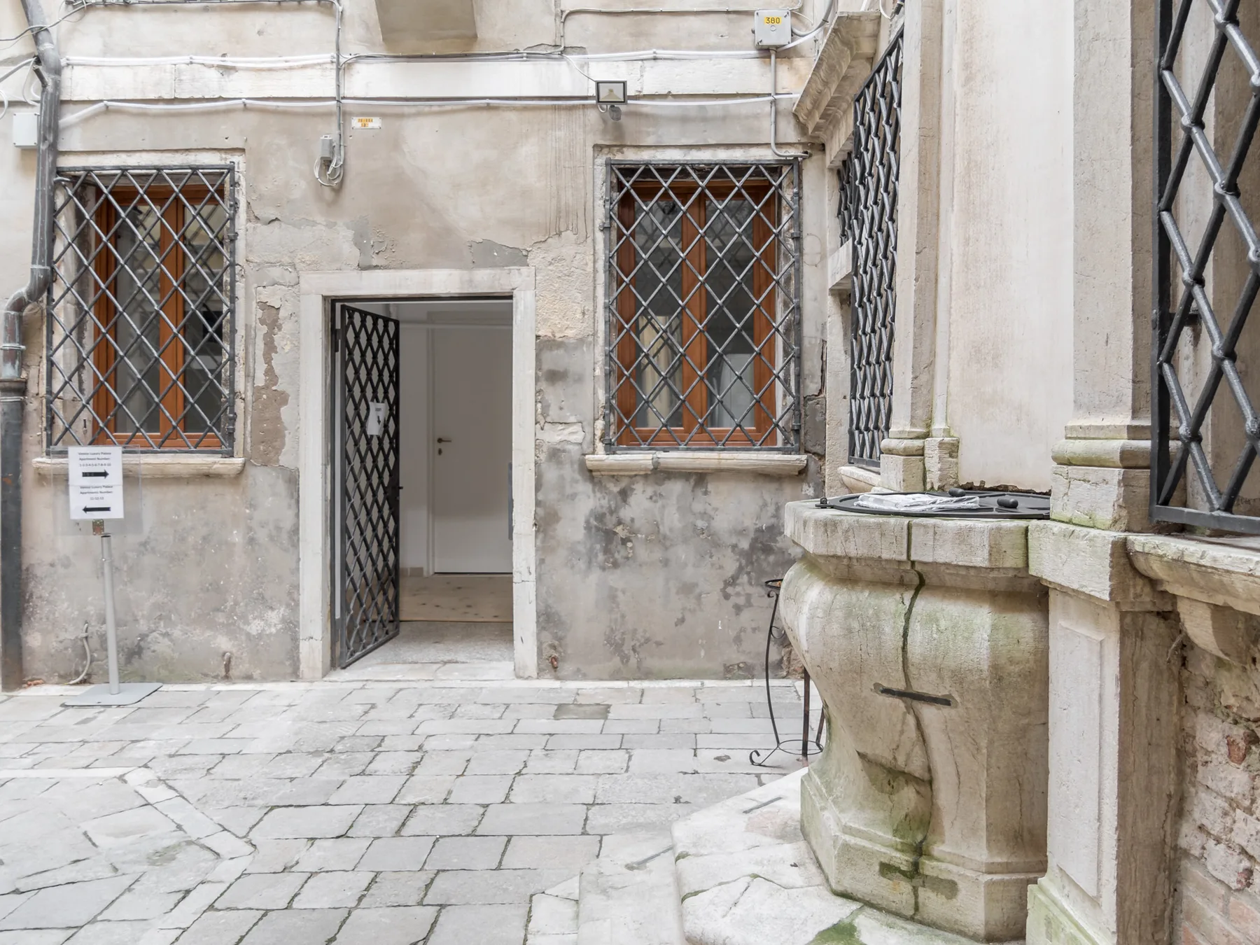 La entrada de un antiguo edificio de piedra da a un patio pavimentado.