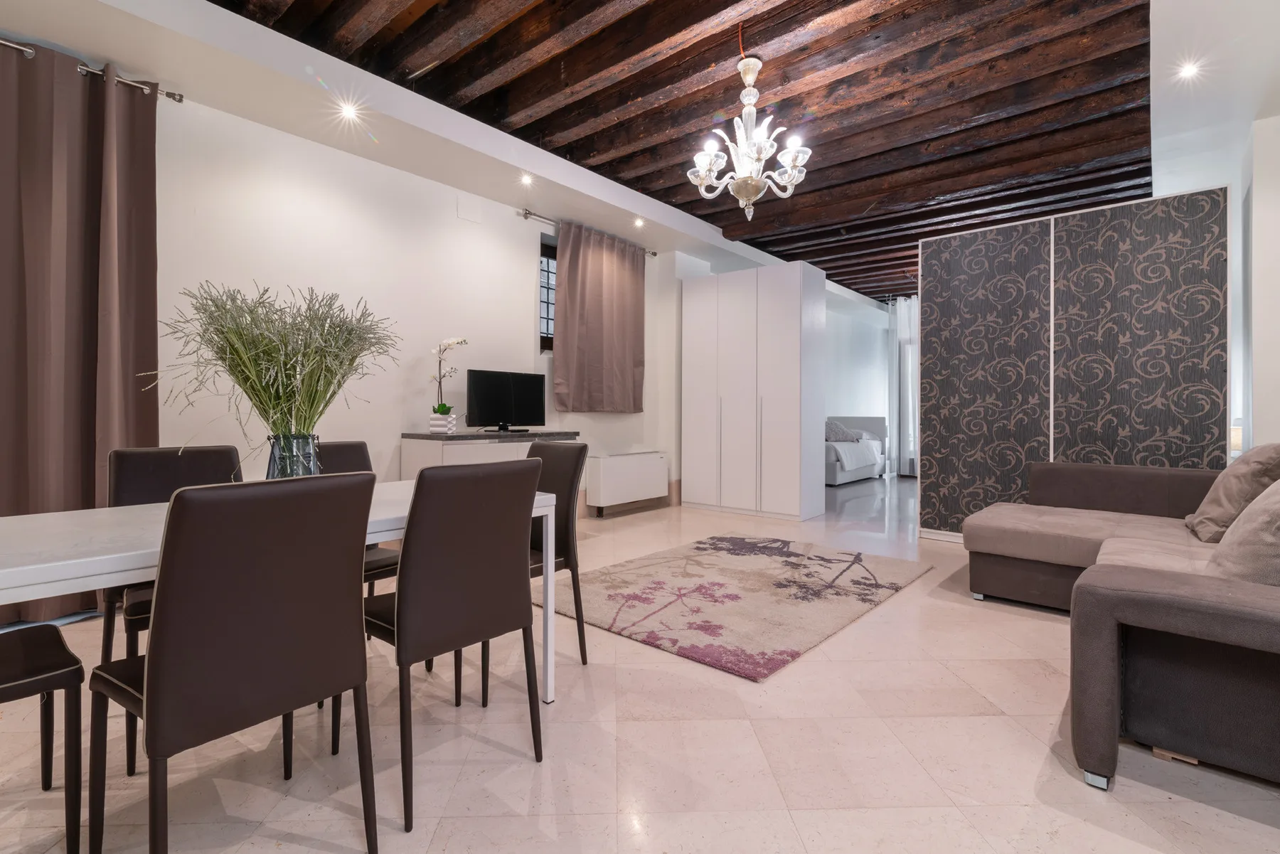 Una zona de comedor y estar con mesa, asientos y una alfombra estampada.