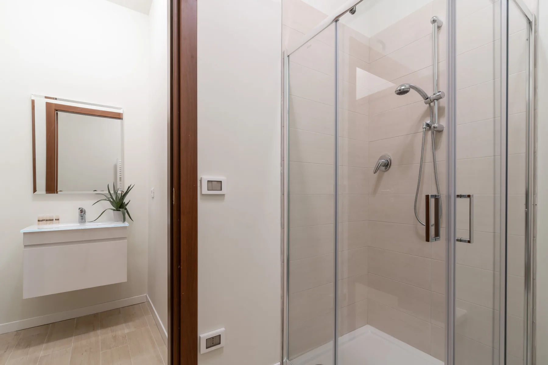 Un baño con ducha de vidrio y lavabo suspendido.