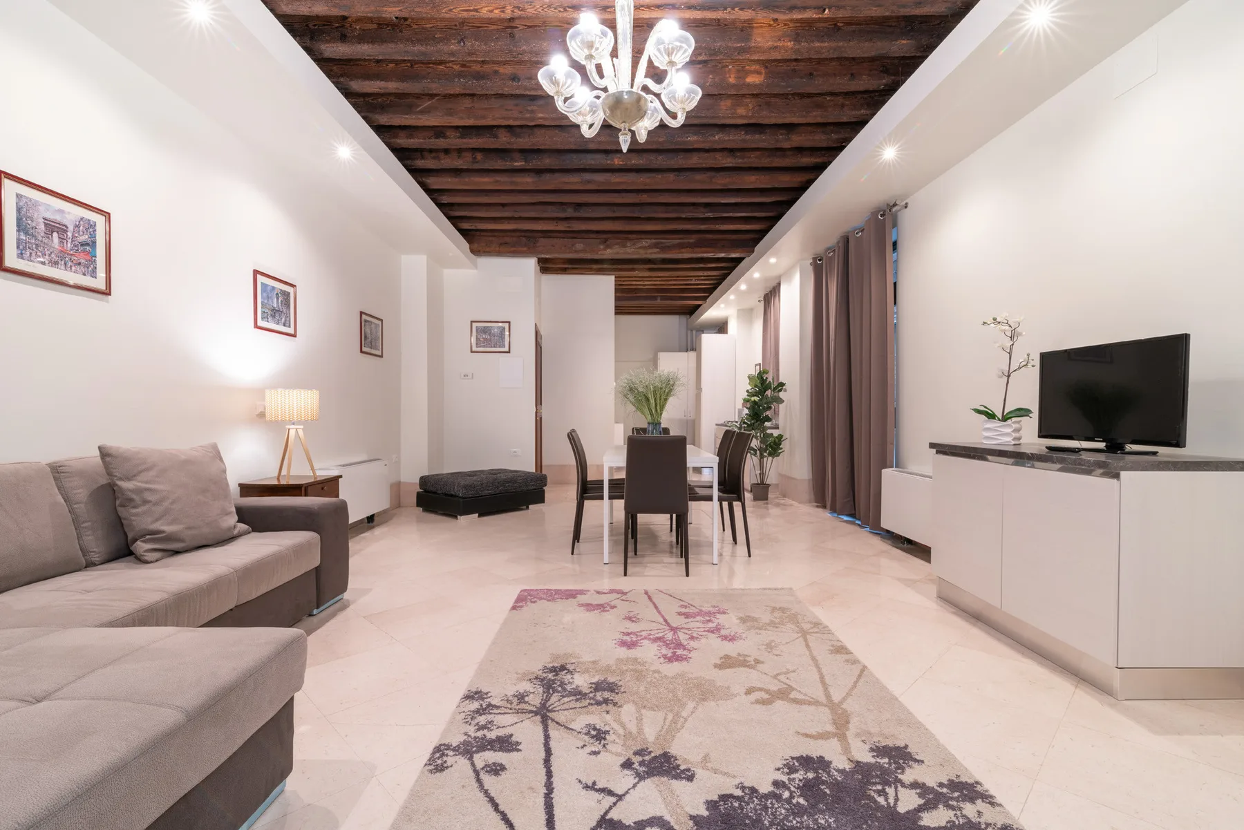 Una sala luminosa con asientos, una mesa de comedor y un televisor.
