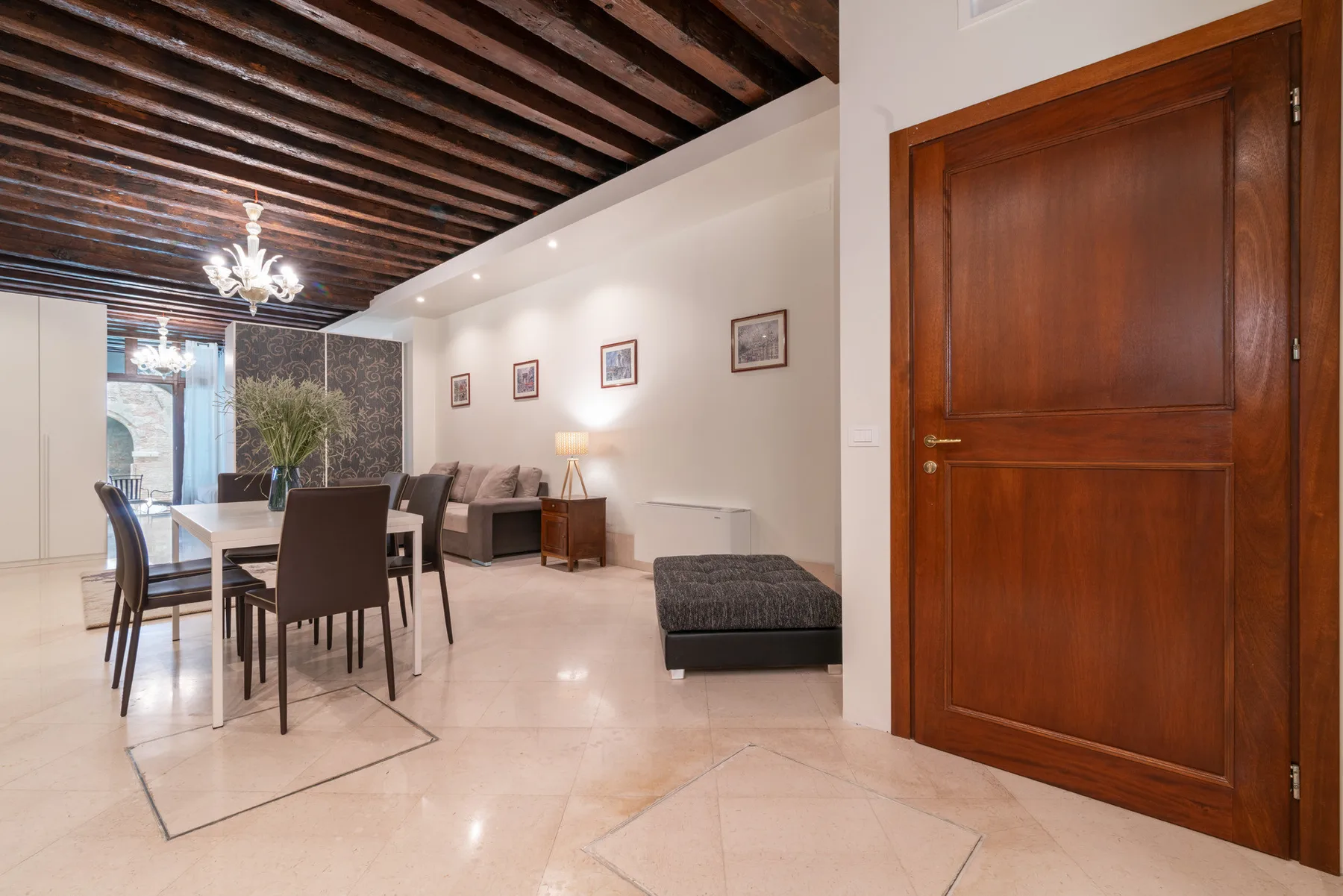 Un comedor y sala de estar con una mesa, asientos y una puerta de madera.