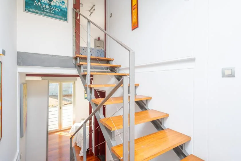 A bright interior staircase with wooden steps and a metal railing.
