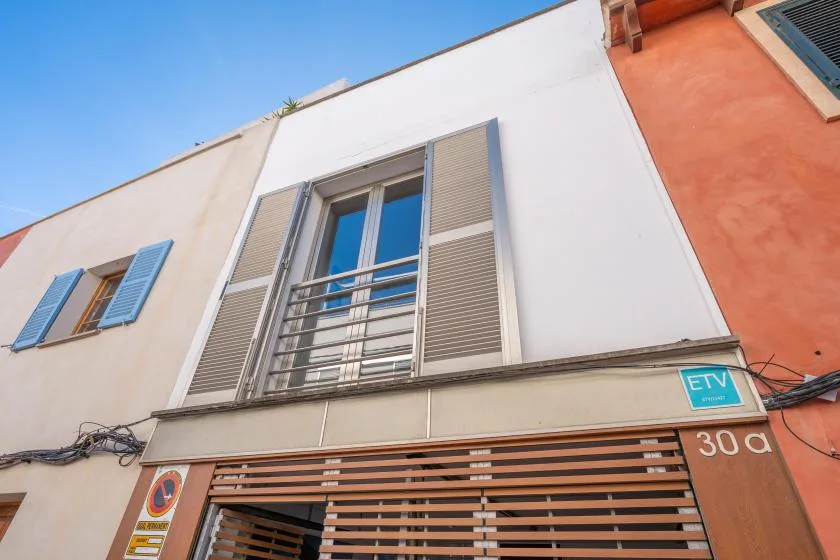 A street-level view of a building facade with shuttered windows and a slatted entrance.
