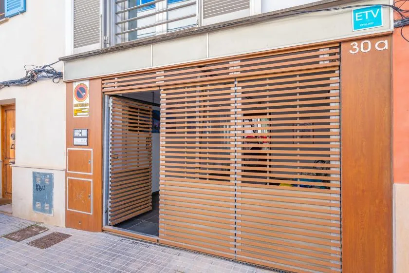A street-facing building entrance with a partially open slatted gate.