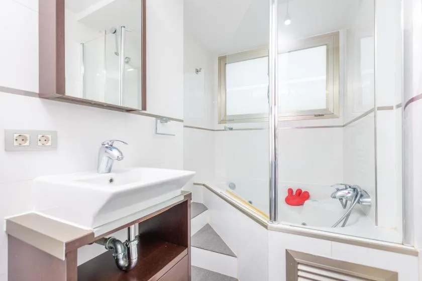 A bright bathroom with a sink, bathtub, and frosted windows.