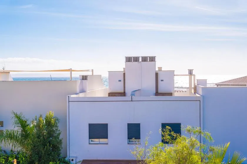 White rooftop structures overlook the sea beneath a clear blue sky.