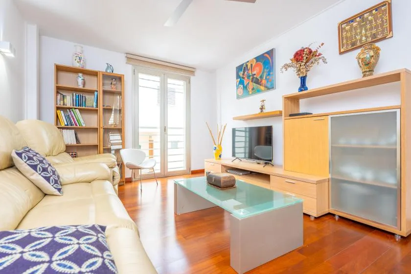 A bright living room with seating, a television, and a glass coffee table.