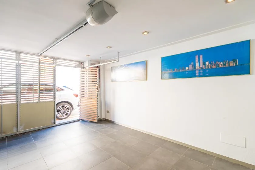 A bright tiled interior with slatted screens, a parked car, and framed artwork.