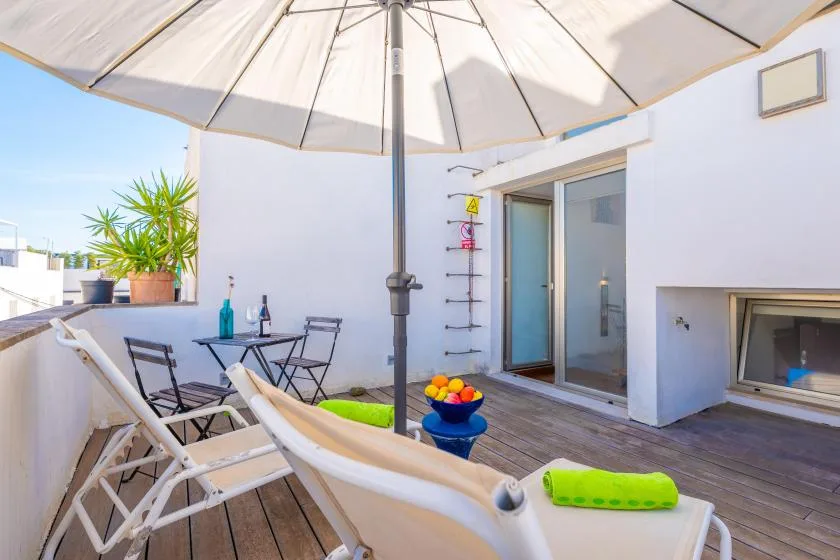 A sunny terrace with lounge seating, a dining table, and sliding glass doors.