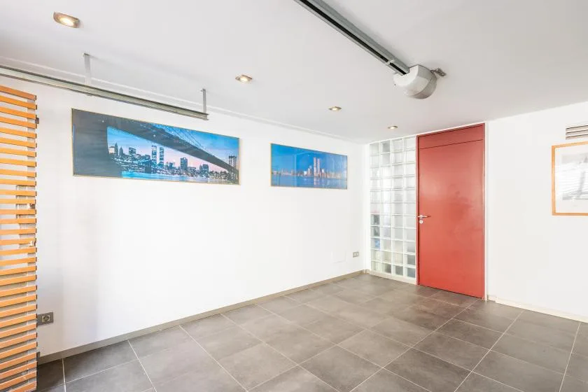 A tiled interior room with a red door and framed city pictures on the wall.