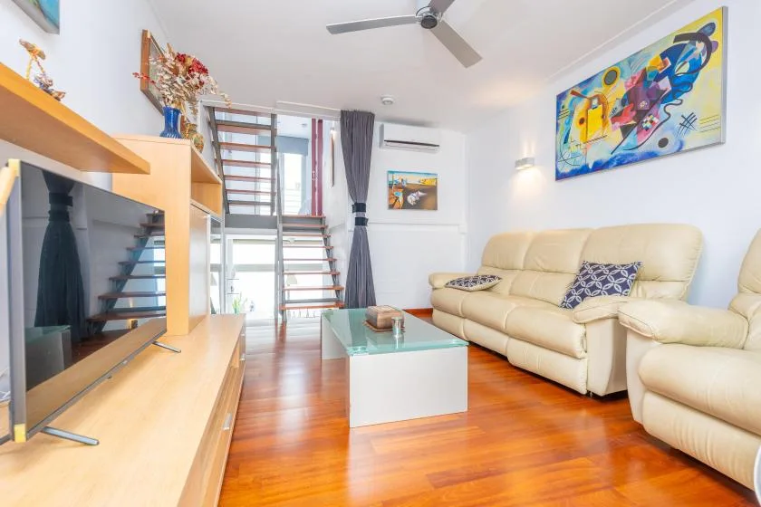 A living room with cream seating, a glass coffee table, and colorful wall art.