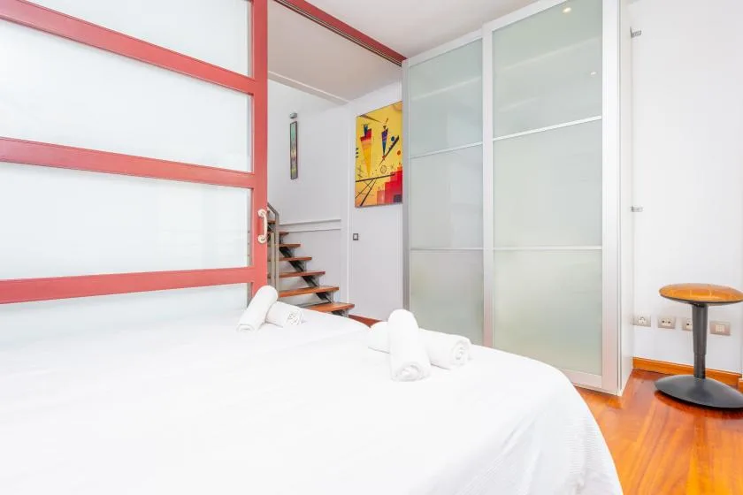 A bright bedroom with a white bed beside frosted glass partitions.