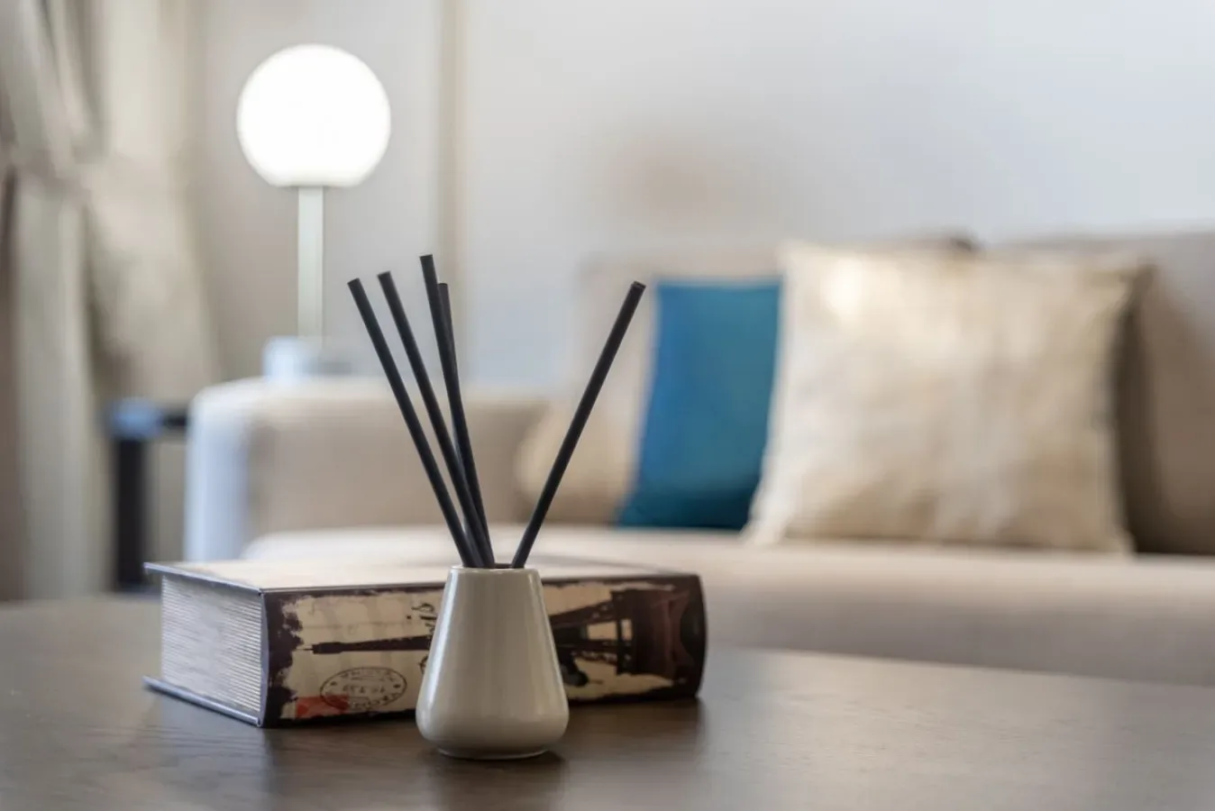 Una zona de estar con una mesa, un libro y un difusor de varillas.