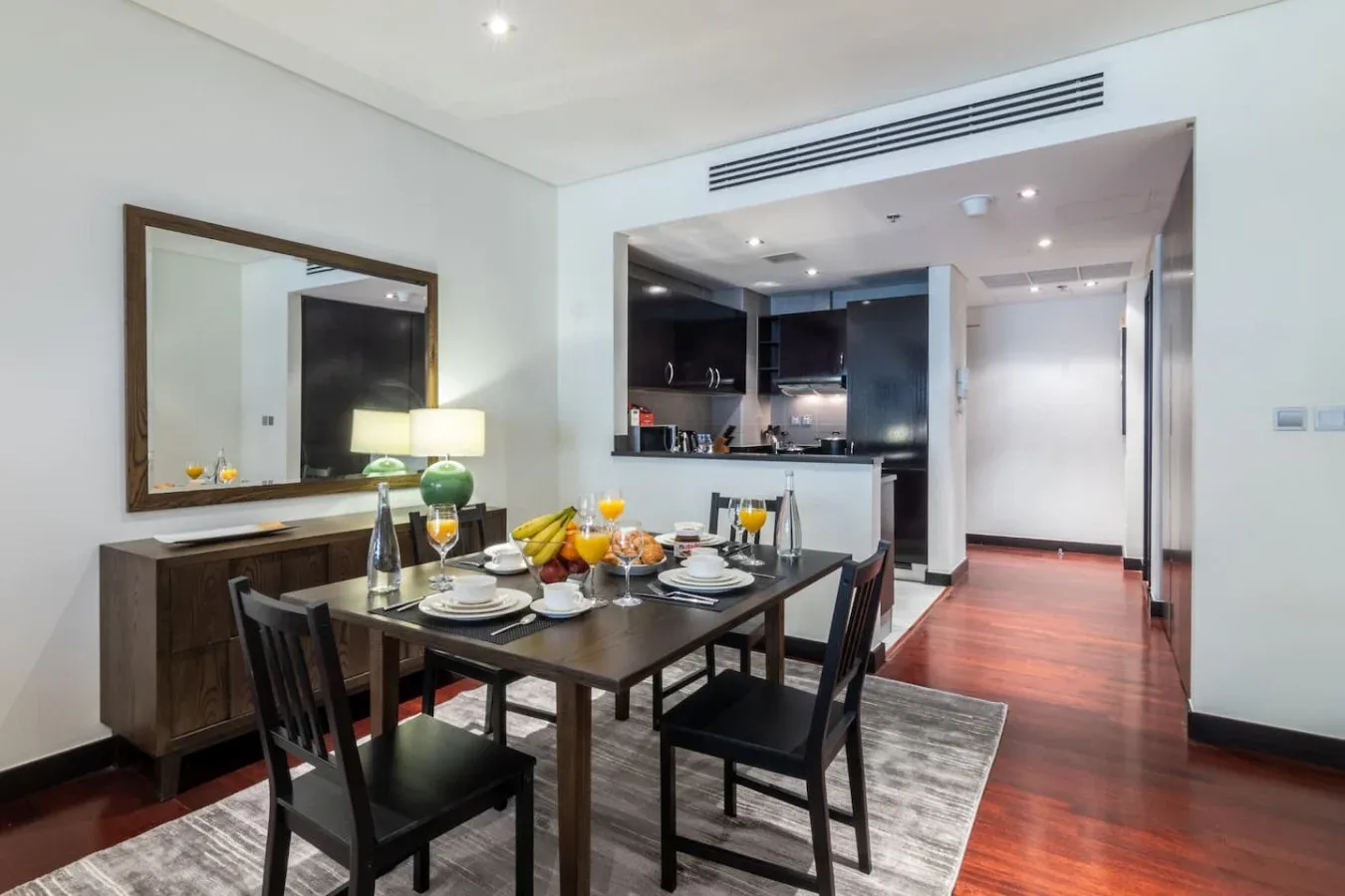 Comedor con la mesa puesta y una cocina abierta al fondo.