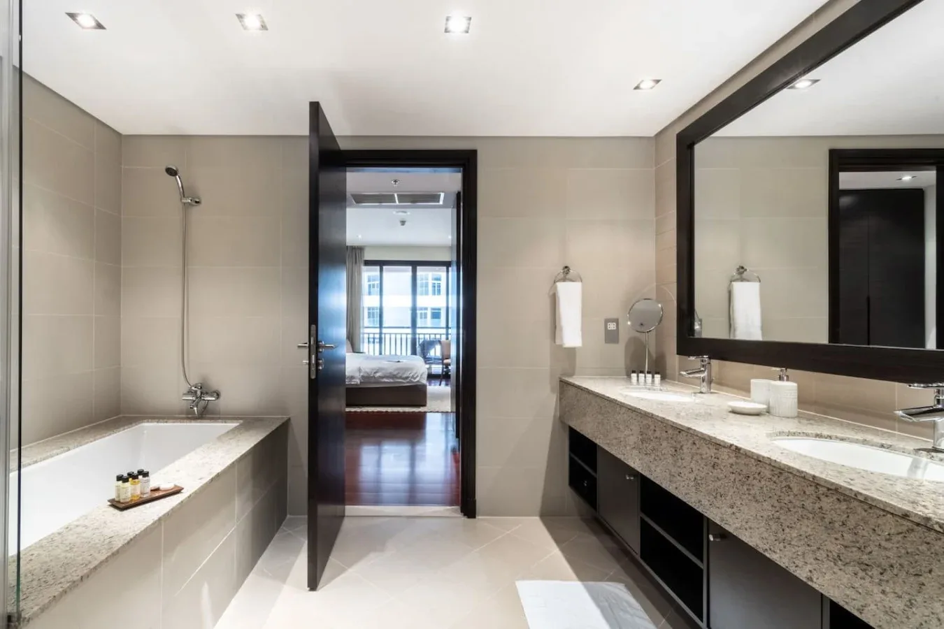Un baño luminoso con bañera, ducha y un tocador largo.
