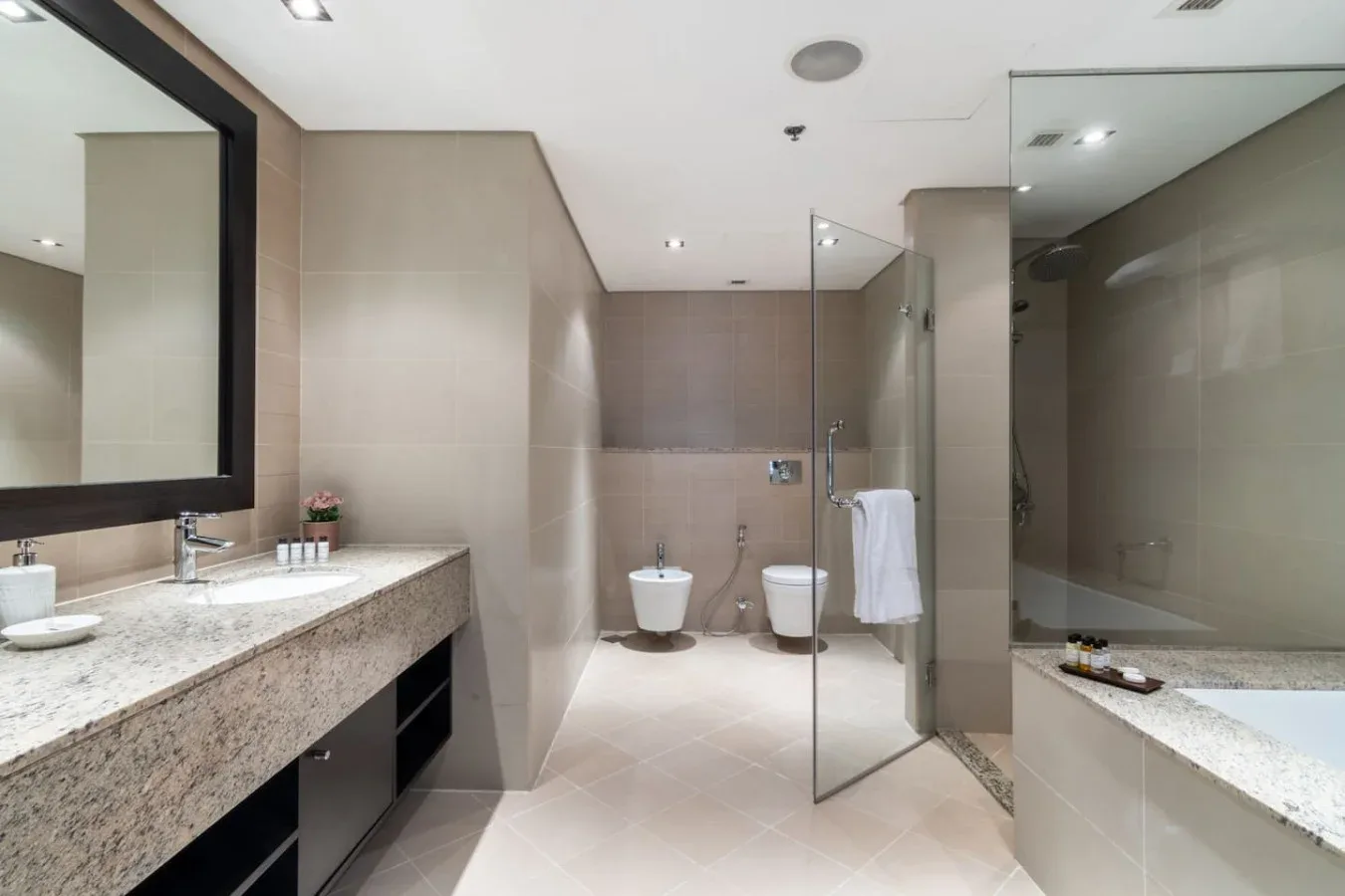 Un baño moderno con lavabo de piedra, inodoro y ducha de vidrio.