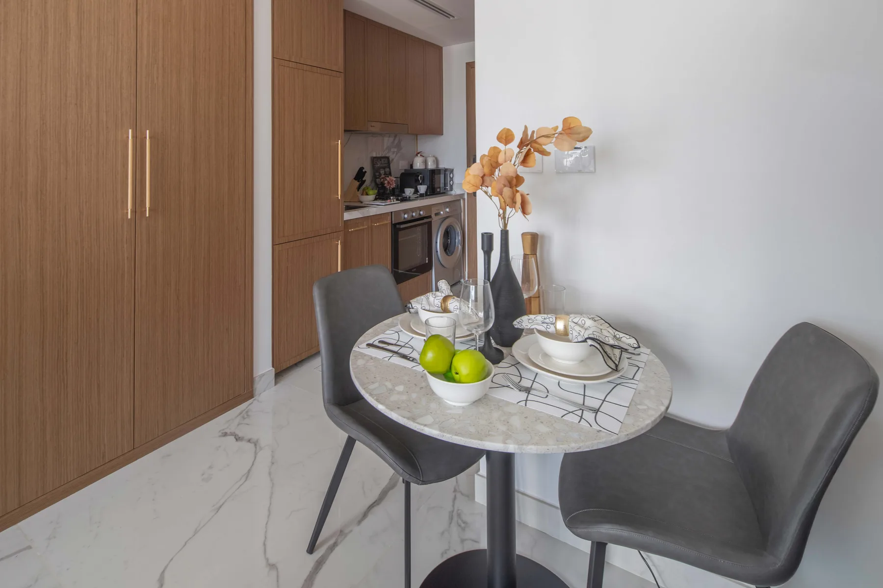 A dining area with a round table set beside a compact kitchen.