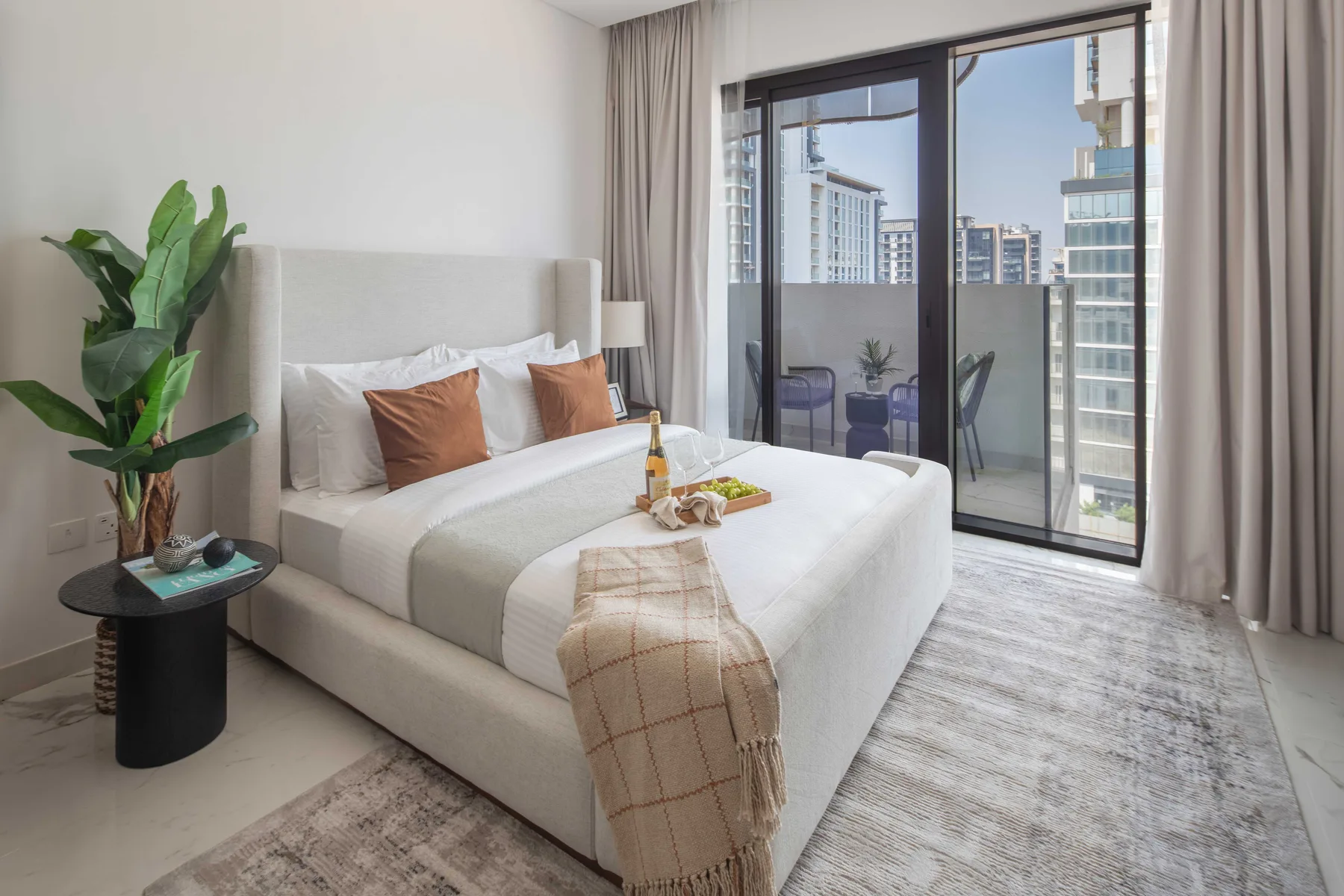 A bright bedroom with a large bed beside a floor-to-ceiling window.