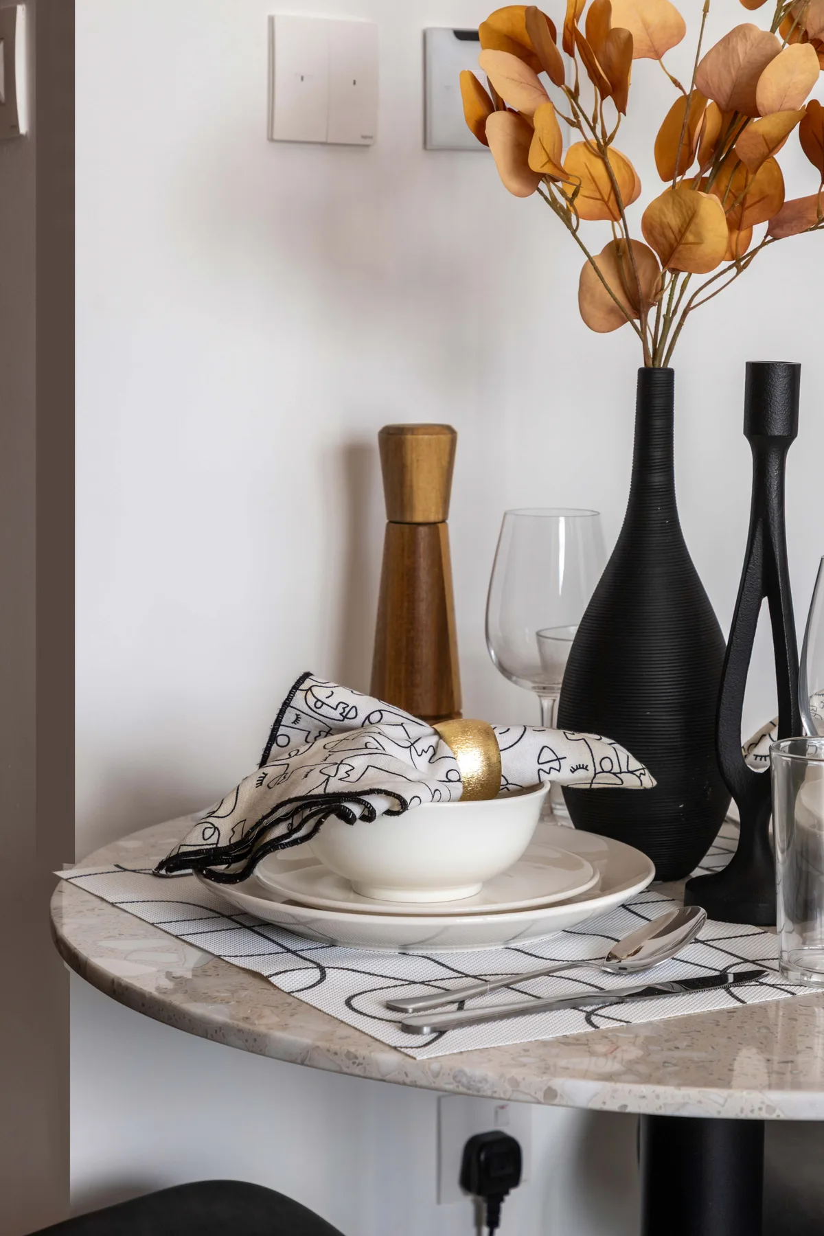A dining table is set with dishes, glassware, and decorative vases.