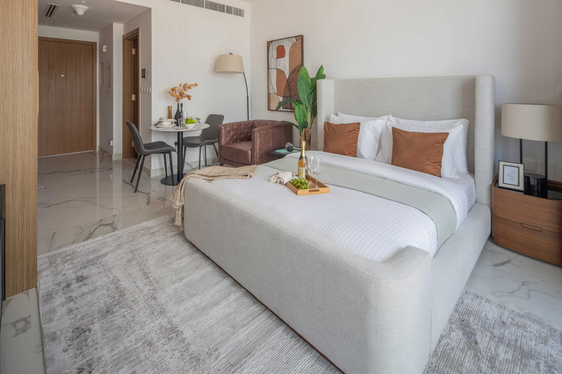 A bedroom with a large bed, a small dining table, and a seating area.