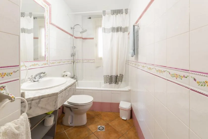 A tiled bathroom with a bathtub, shower curtain, sink, and toilet.