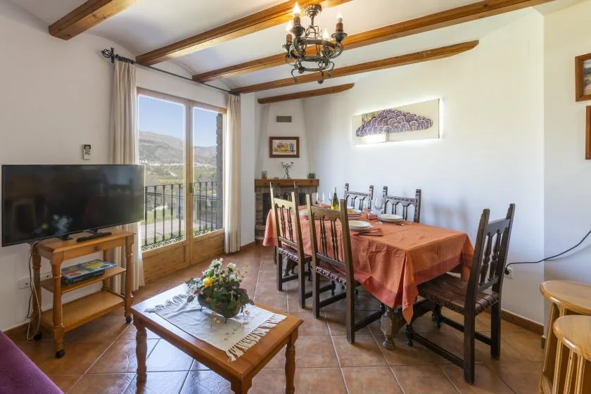 A dining and living area with a long table, seating, and large glass doors.