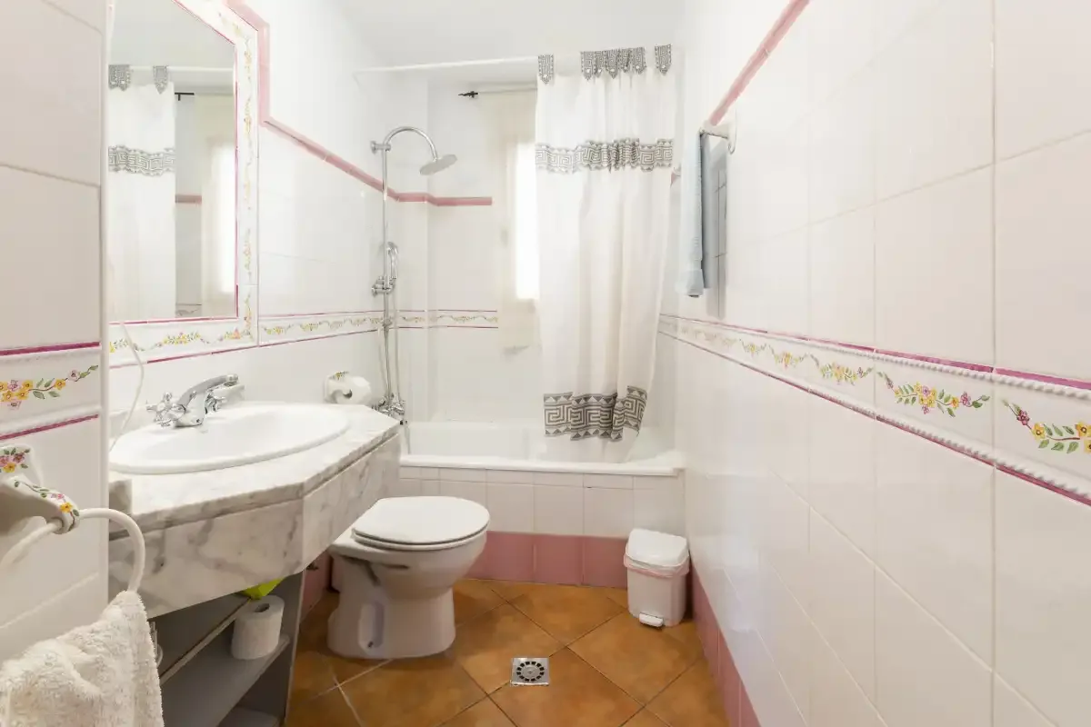 A bathroom with a sink, toilet, and bathtub behind a curtain.